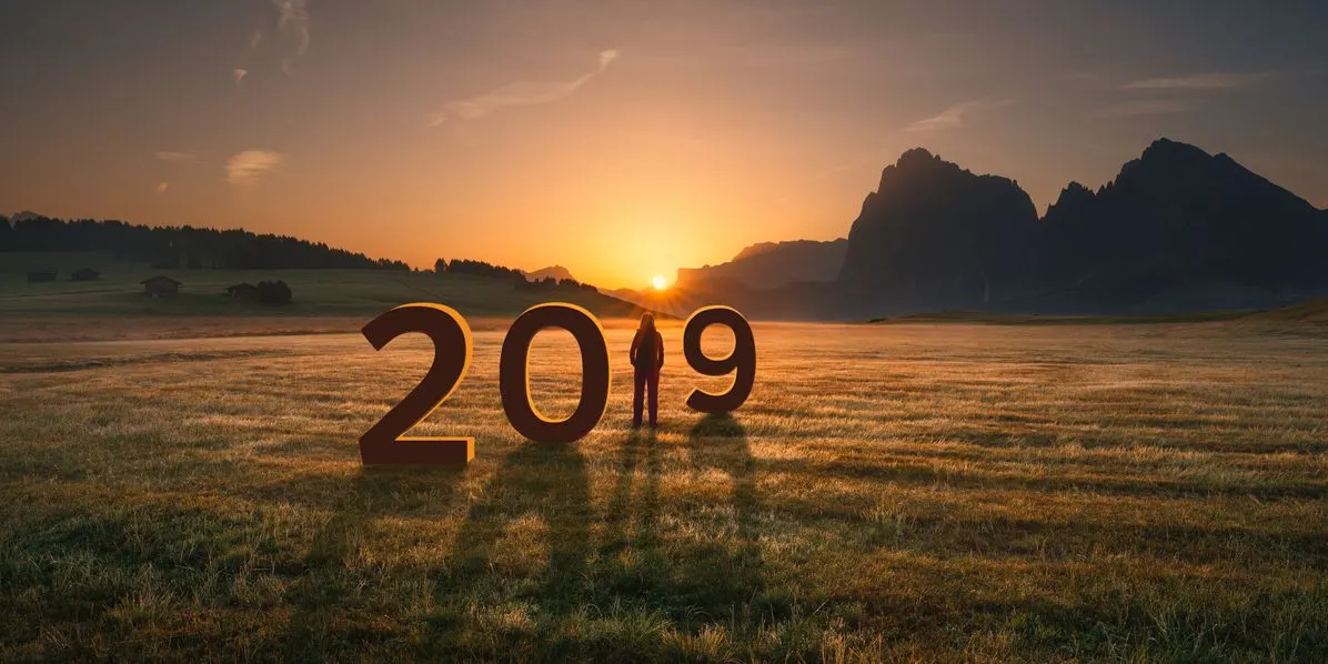 Weite Landschaft mit Bergen im Hintergrund und den Zahlen 2019 bei Sonnenaufgang.