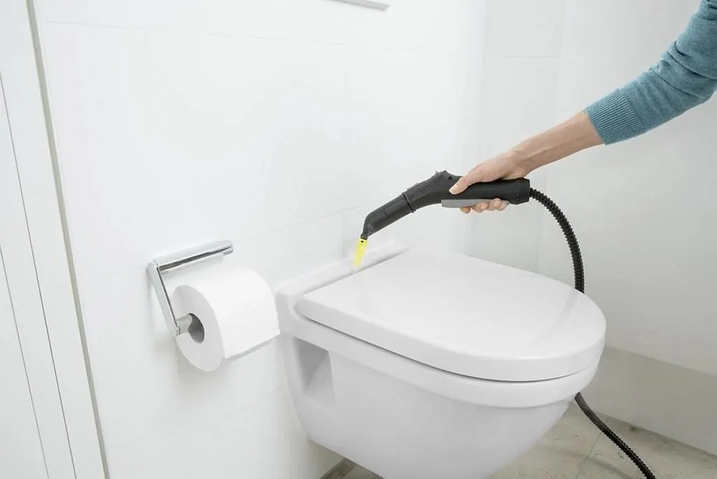 Hand reinigt Toilettenrand mit einem Dampfreiniger