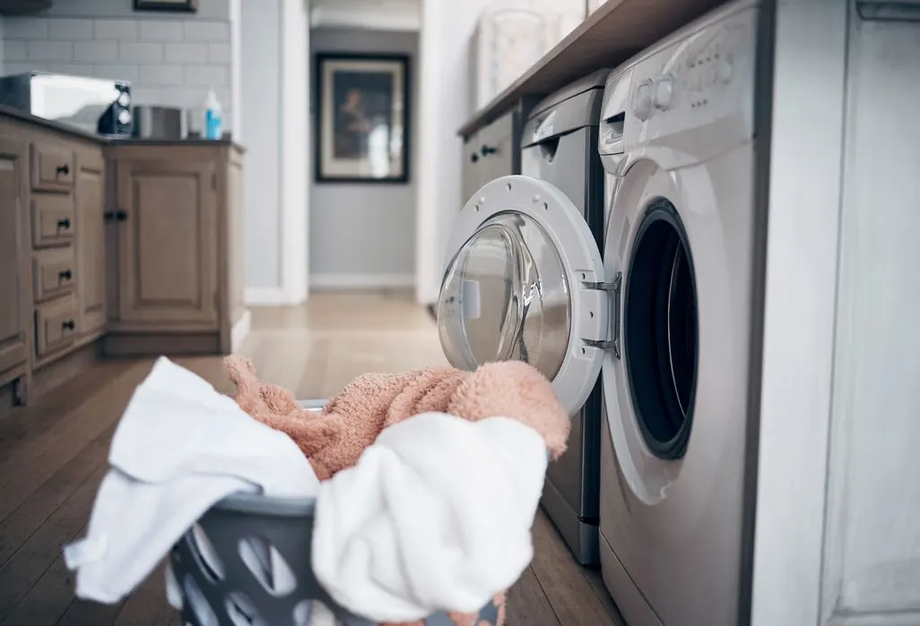 Wäschekorb mit Handtüchern vor einer offenen Waschmaschine