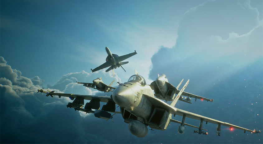 Mehrere Kampfflugzeuge fliegen in Formation durch einen bewölkten, blauen Himmel, wobei ein Jet im Vordergrund und die anderen leicht versetzt dahinter zu sehen sind