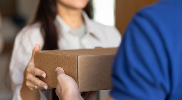 Frau übergibt ein Paket an den Paketboten