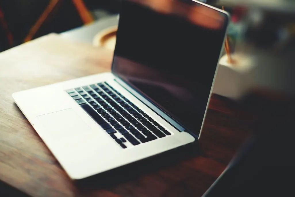 Frau zeigt frustriert auf Laptop-Bildschirm am Arbeitsplatz