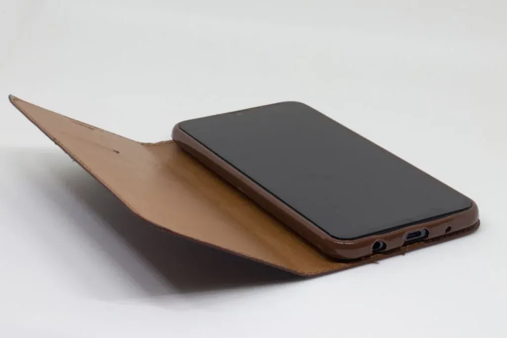 Braune Handy Klapphuelle mit Smartphone liegt aufgeklappt am Tisch