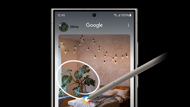 Auf einem Smartphone-Bildschirm wird eine Google-Suche in einem Schlafzimmer mit Lichterketten und einer Zimmerpflanze angezeigt. Ein Stift tippt auf das Display.