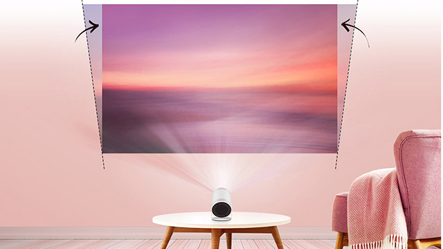 Projektor auf einem Tisch projiziert ein Landschaftsbild an die Wand. Ein rosa Sessel steht daneben.