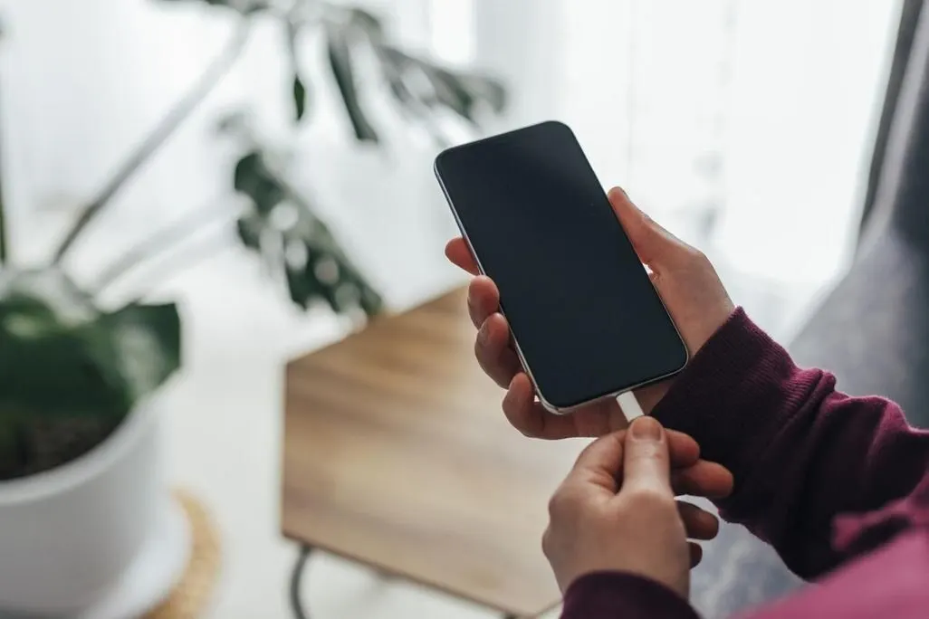 Person steckt Ladekabel in ein Smartphone