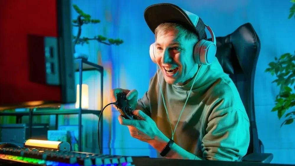 Jugendlicher sitzt mit Headset auf einem Gamingsessel und hat Controller in der Hand