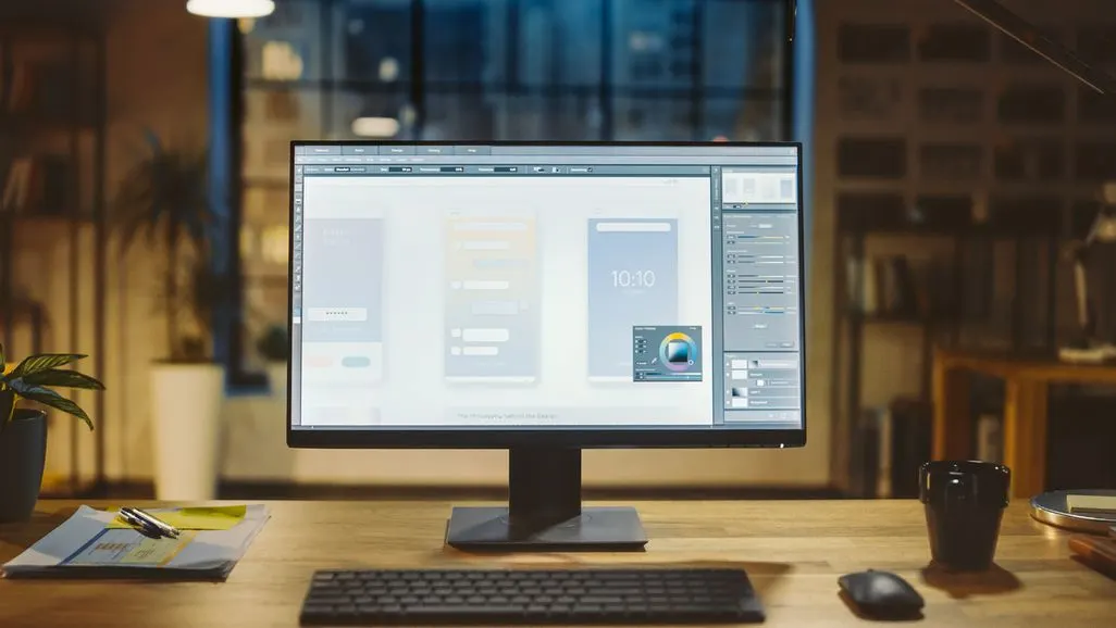 Ein großer Monitor steht auf einem Schreibtisch und zeigt eine Designsoftware.