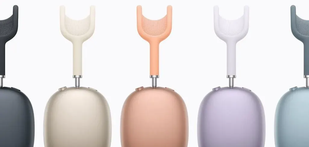 Fünf Wireless-Kopfhörer in verschiedenen Farben: Schwarz, Creme, Pfirsich, Weiß, Blaugrau. Moderne Over-Ear-Kopfhörer mit metallischen Halterungen nebeneinander.