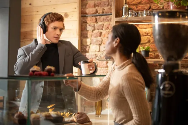 Junger Mann mit Kopfhörer spricht mit Frau aus Restaurant