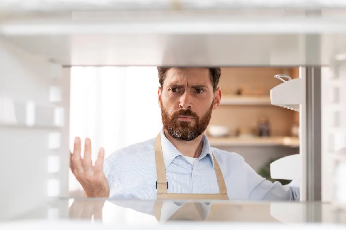 ein Mann schaut verwundert in eine Kühlschrank