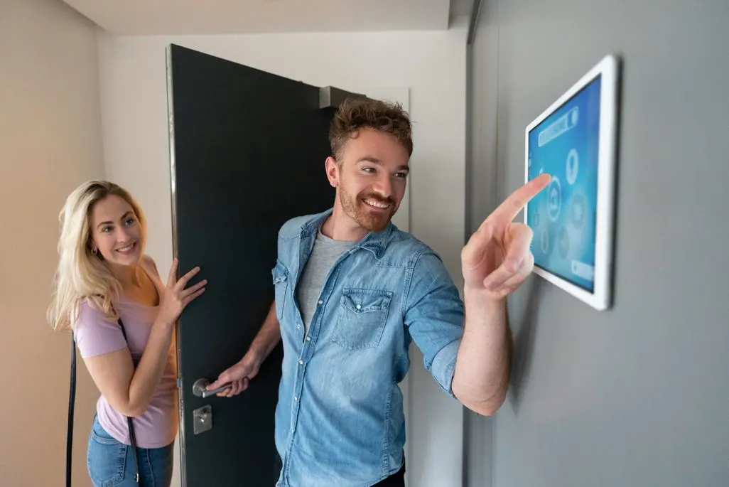 Mann tippt auf ein Smart Home Bedienfeld an der Wand