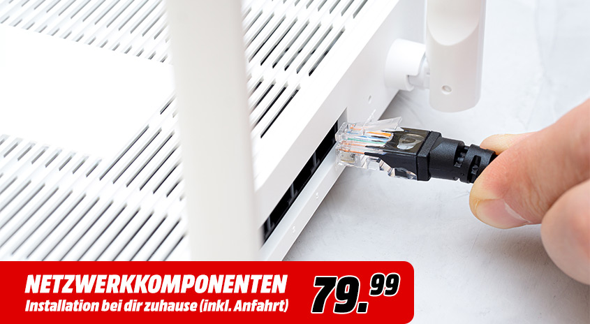 Ein Ethernet-Kabel wird in einen weißen Router mit Antennen gesteckt. Im Vordergrund ist eine rote Preiswerbung zu sehen.