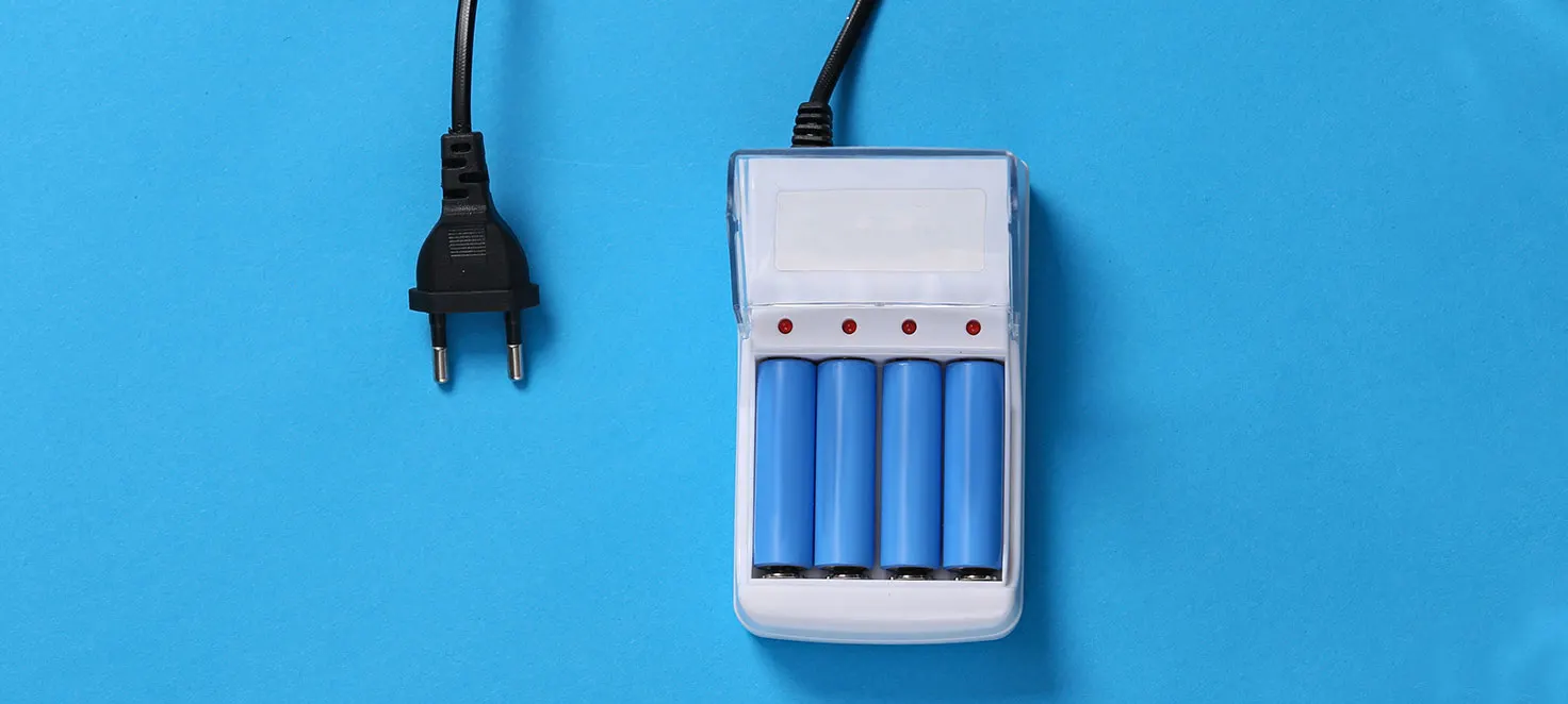 Ein Ladegerät mit vier blauen Batterien und einem Stecker auf blauem Hintergrund.