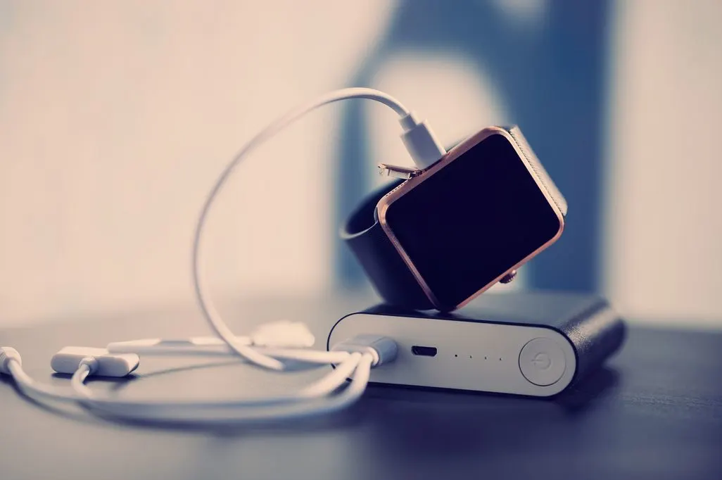 Eine Smartwatch wird mit einem Ladekabel an einer Powerbank aufgeladen.