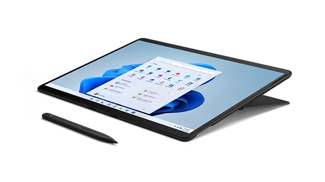 Ein schwarzes Tablet mit einem blauen Hintergrundbild und einem geöffneten Fenster liegt neben einem Stift auf einem weißen Hintergrund.