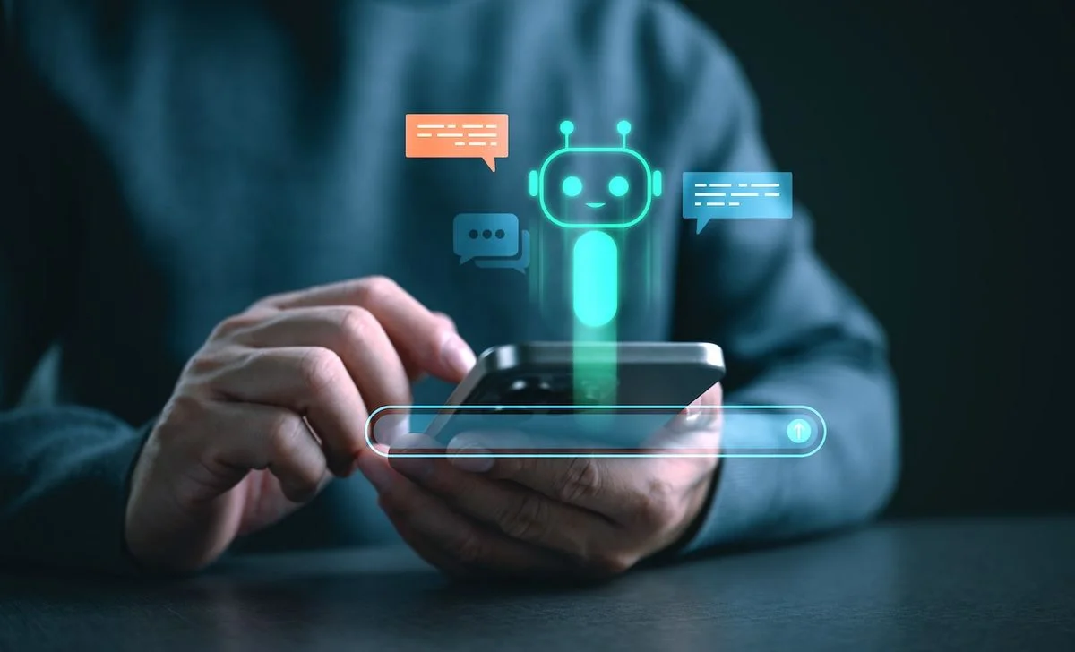 Hand hält Smartphone mit holografischem Chatbot-Interface und leuchtenden Sprechblasen, symbolisiert KI-Kommunikation und digitale Assistenz.