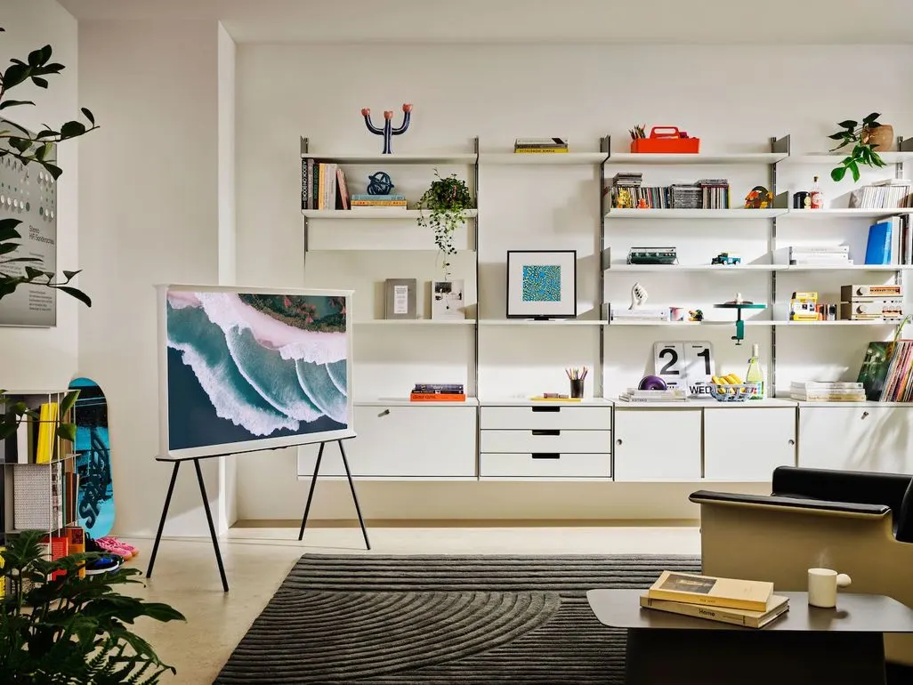 Modernes Wohnzimmer mit Fernseher auf Staffelei und Regalwand im Hintergrund.