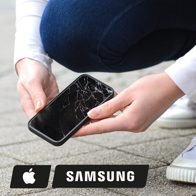 Ein Smartphone mit einem zerbrochenen Bildschirm wird von zwei Händen vor einem Hintergrund aus Pflastersteinen gehalten.