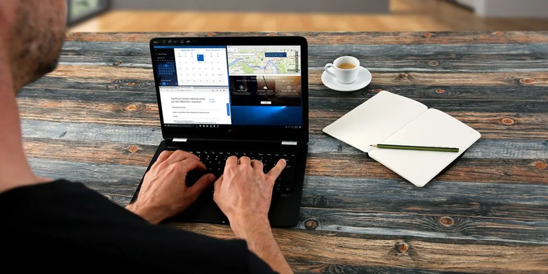 Person arbeitet an einem Laptop auf einem Holztisch