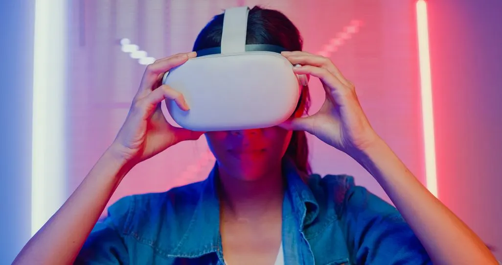 Person setzt sich eine VR-Brille auf, umgeben von buntem Licht.