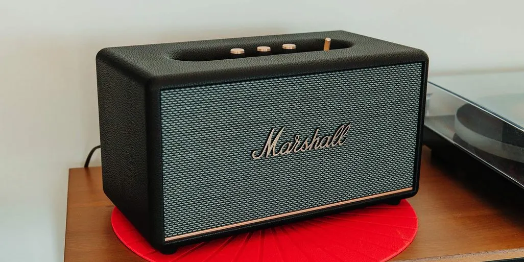 Ein Marshall Lautsprecher steht auf einem roten Untersetzer auf einem Holzregal.