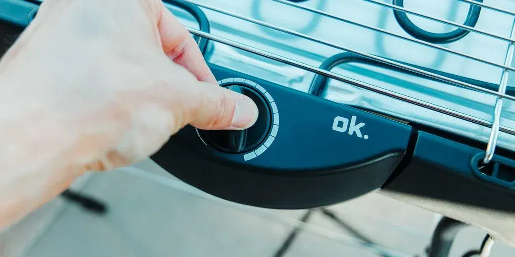 Drehregler eines ok-Elektrogrills wird von einer Hand bewegt