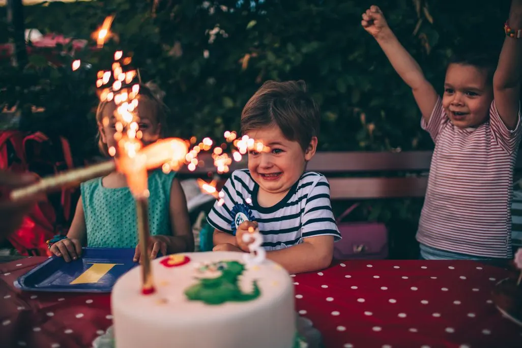 Kinder feiern Geburtstag an einem Tisch mit Kuchen und Wunderkerzen