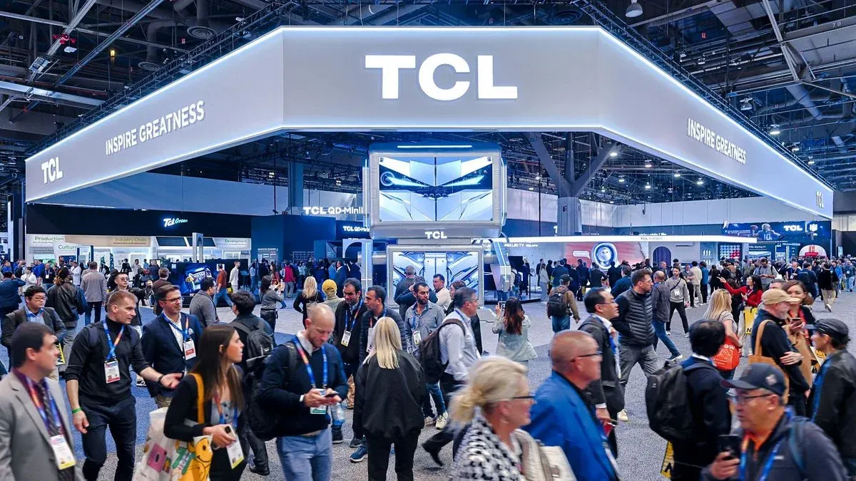 Messebesucher laufen durch eine große Halle mit TCL Stand und Leuchtreklame.