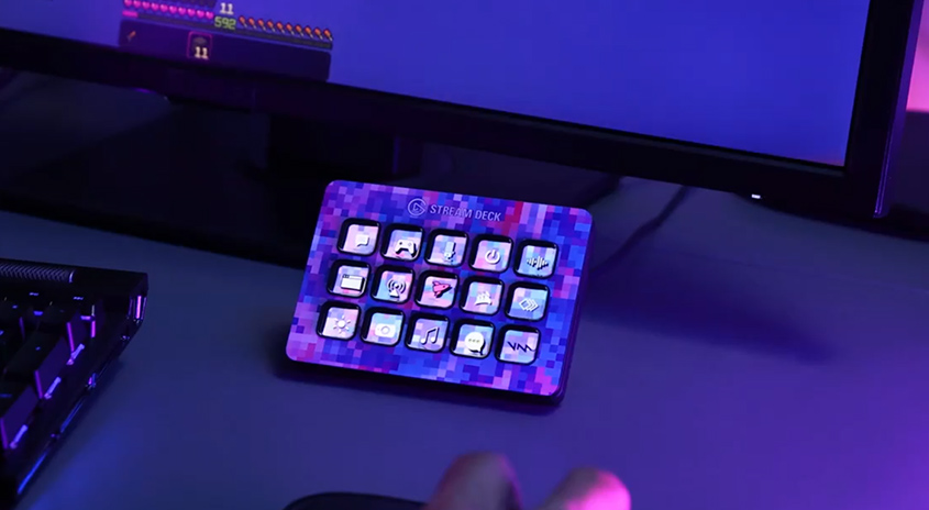 Auf einem Schreibtisch steht ein Stream Deck mit bunten Tasten neben einer schwarzen Tastatur und einem Monitor.