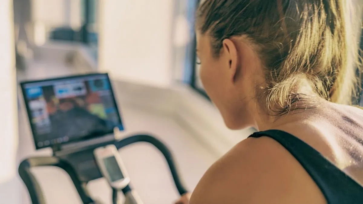 Eine Frau trainiert auf einem Heimtrainer und schaut auf einen Bildschirm.
