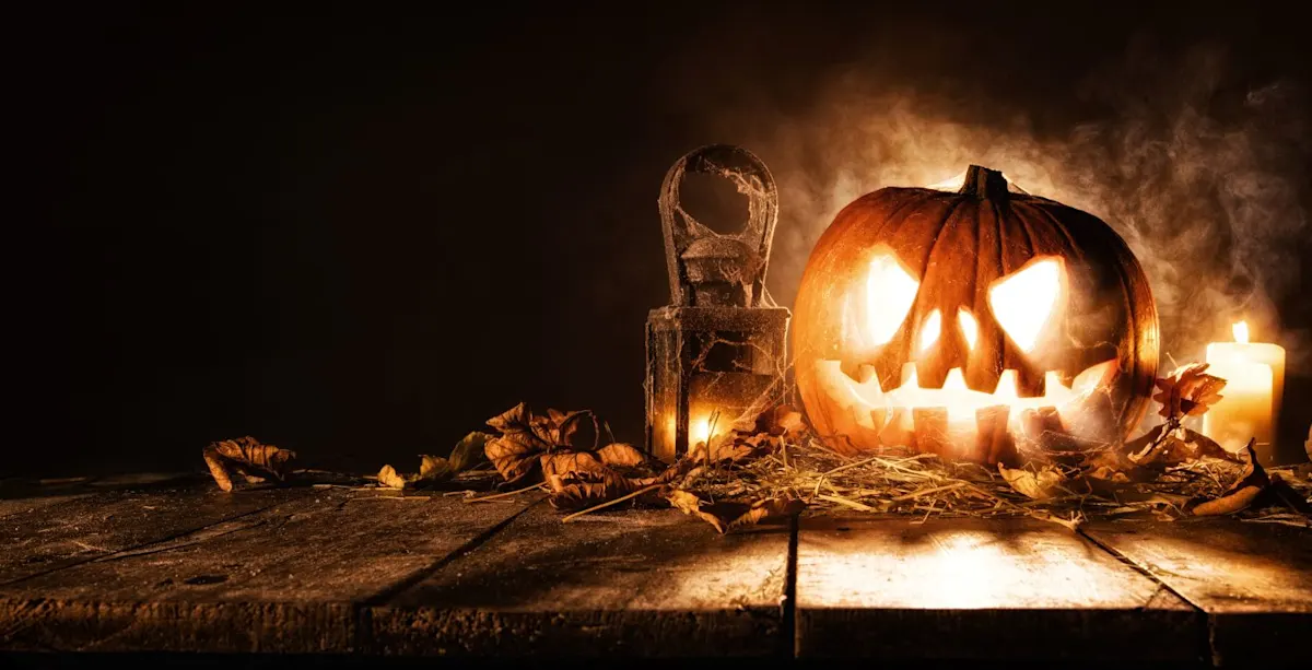 Eine gruselig beleuchtete Halloween-Kürbislaterne mit geschnitztem Gesicht steht auf einem alten Holztisch, umgeben von trockenem Laub, Spinnweben, einer alten Laterne und brennenden Kerzen im rauchigen Halbdunkel.