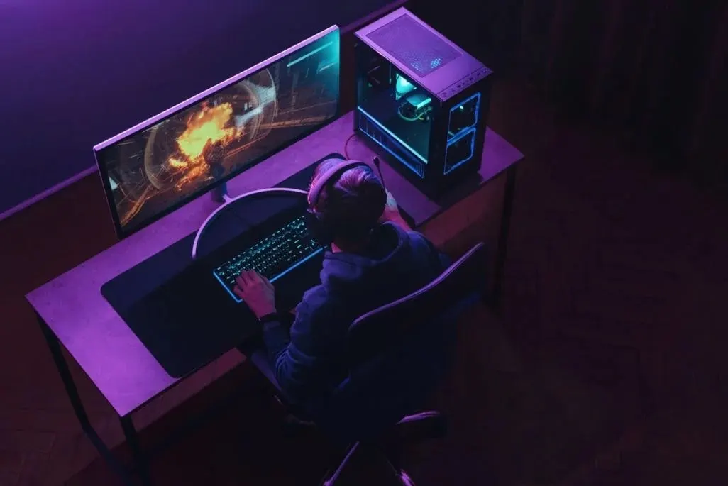Jugendlicher mit Headset sitzt vor seinem Gaming-Setup und spielt