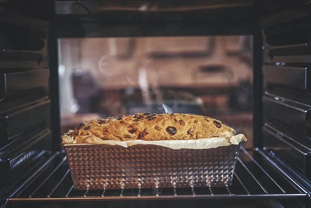 Frisches Früchtebrot mit Rosinen in Backform im vorgeheizten Ofen während des Backvorgangs.