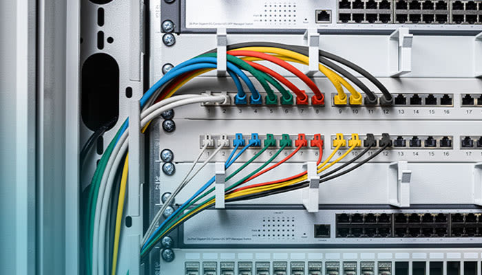Nahaufnahme eines Netzwerkschranks mit sehr ordentlich verlegten, farbig sortierten Patchkabeln.