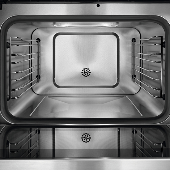 Ein leerer, sauberer, silberfarbener Backofen mit Rosten an den Seiten und einer Lüftungsöffnung in der Mitte.