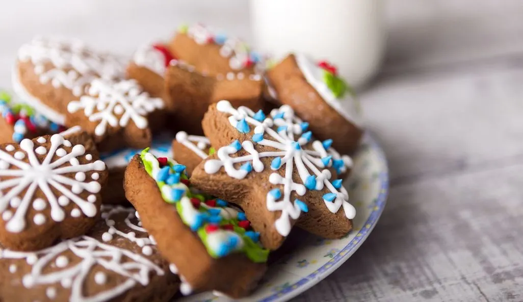Weihnachtliche Kekse mit Zuckerguss verziert auf einem Teller.