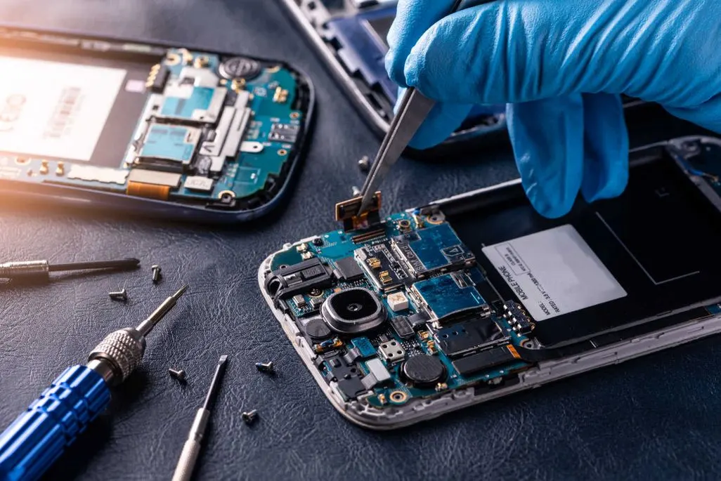 Nahaufnahme von geoeffnetem Smartphone das mit Werkzeug repariert wird