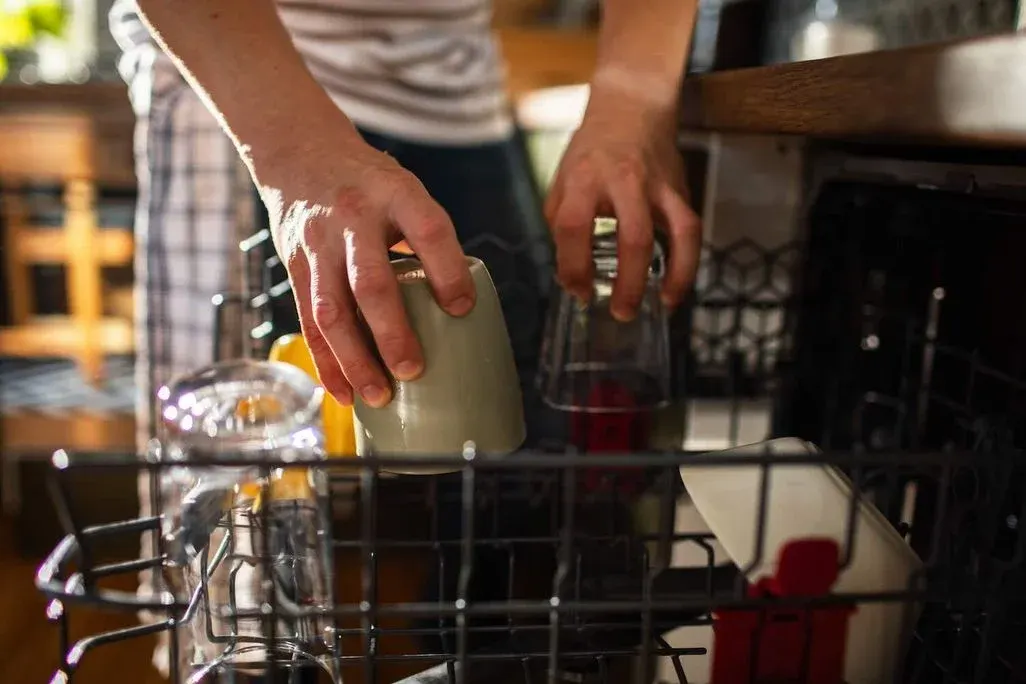 Ein Bild von einer Person die einen Geschirrspüler befüllt