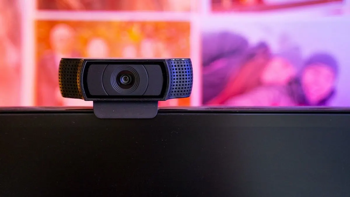 Externe Webcam steht auf Monitor vor buntem Hintergrund.