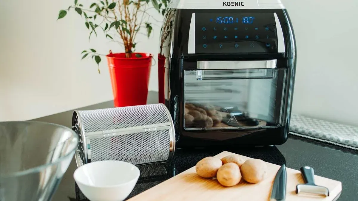 Koenic Heissluftfritteuse auf einem Tisch davor ein Brett mit Kartoffeln