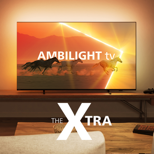 Ein Fernseher zeigt Pferde vor einem orangefarbenen Himmel. "Ambilight TV" steht auf dem Bildschirm. Der Fernseher steht auf einem Tisch.
