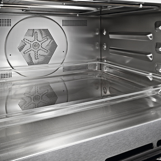 Innenraum eines Edelstahl-Backofens mit Lüfterabdeckung und transparentem Fach. Metallische Oberflächen und perforierte Elemente sichtbar.