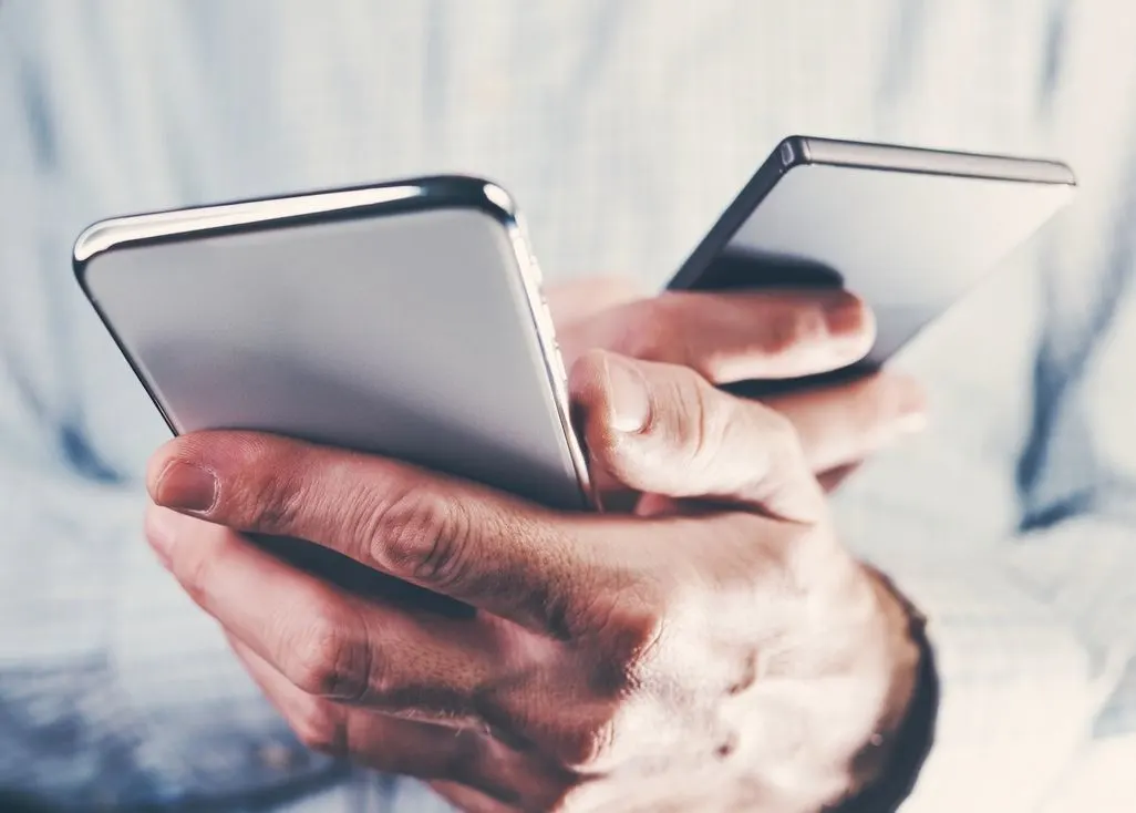 Zwei Hände halten jeweils ein Smartphone nebeneinander.