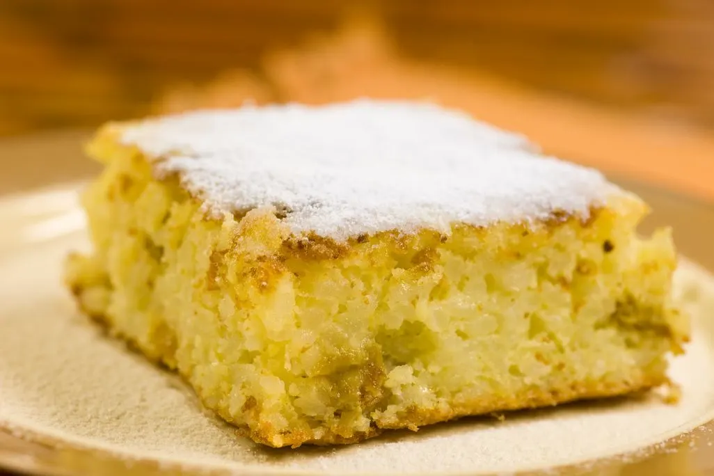Stück saftiger Reiskuchen mit Puderzucker bestäubt auf einem Teller.