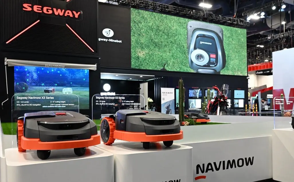 Zwei orange-schwarze Mähroboter der Marke Segway stehen auf einer Messe