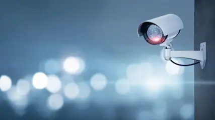 Überwachungskamera ist an einer Wand montiert und leuchtet mit roter LED.
