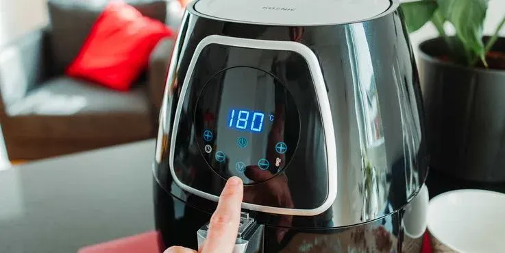 Die Temperatur einer schwarzen Koenic Heißluftfritteuse wird auf 180 Grad gestellt.