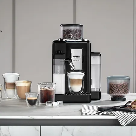 Eine Kaffeemaschine mit Kaffeebohnen steht auf einer Theke. Es gibt verschiedene Getränke, darunter Kaffee und Milch.