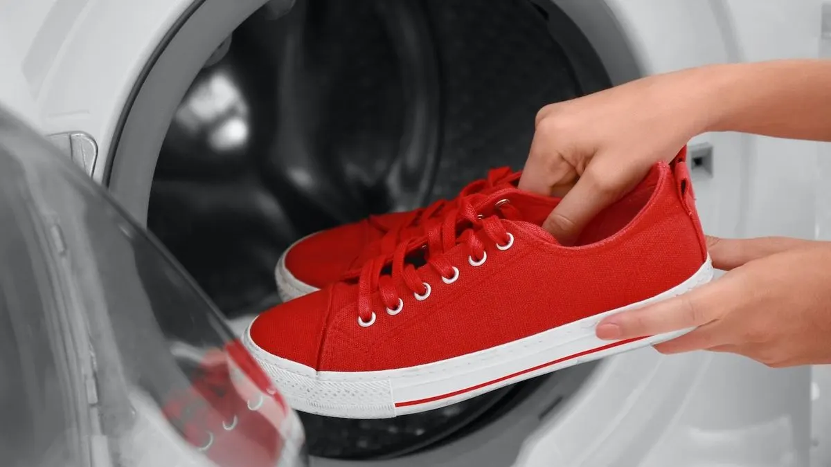 Rote Stoffturnschuhe werden in eine Waschmaschine gelegt